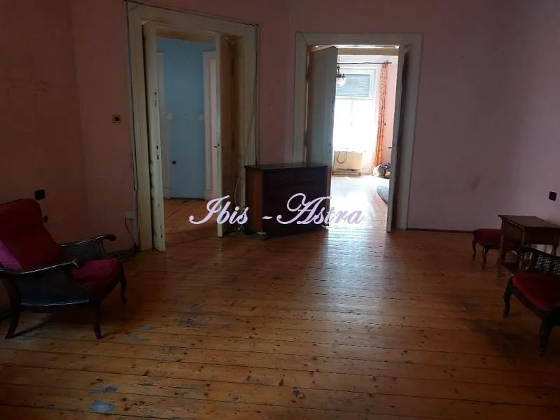 Spacious living room with wooden flooring and a view of other rooms.