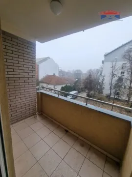 Natkriveni balkon sa popločanim podom i pogledom na okolne zgrade. - image 7