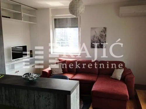 Living room with a red sectional sofa and TV unit.