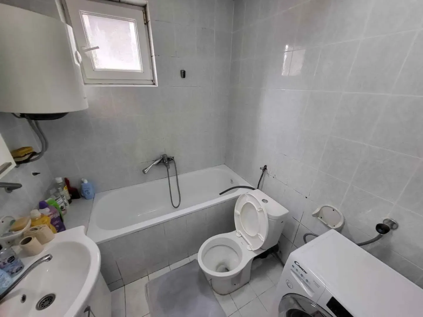 Manje kupatilo sa kadom, wc šoljom, umivaonikom i mašinom za veš.