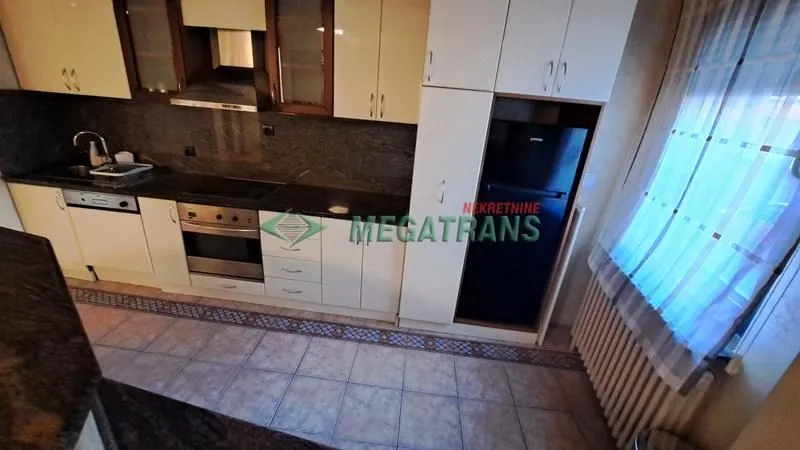 Kuhinja opremljena elementima, ugradnim uređajima i frižiderom.