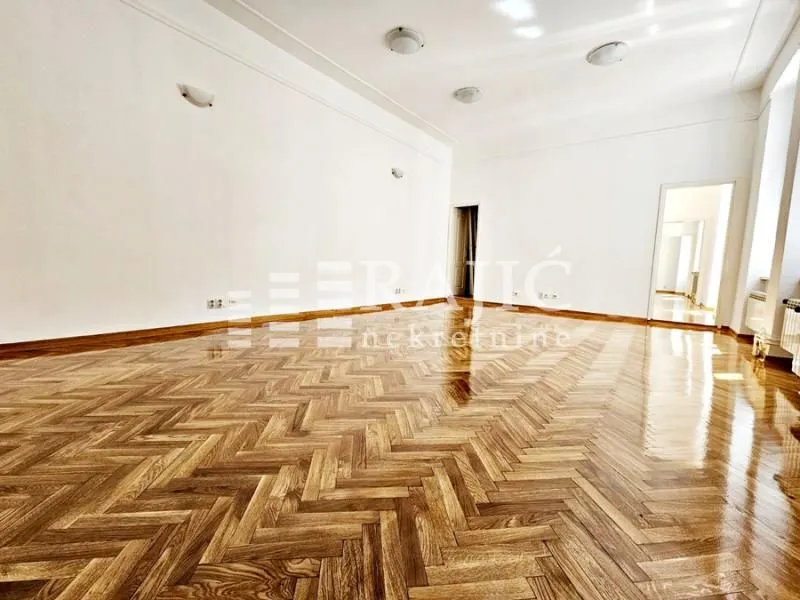 Empty bright room with parquet flooring and white walls.