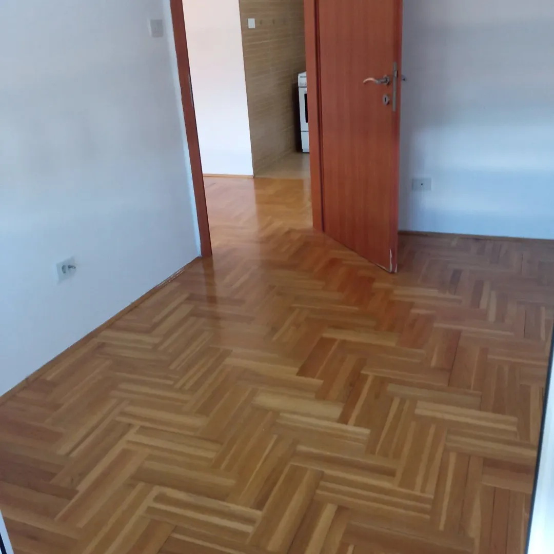 An empty room with parquet flooring and an open door.