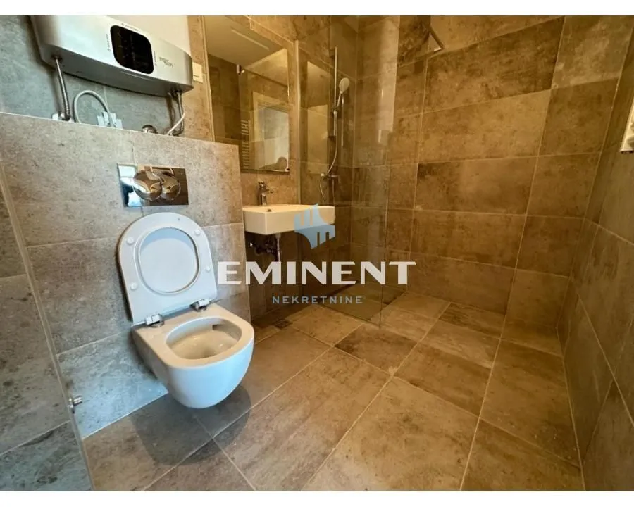 Tiled bathroom with a walk-in shower and a wall-mounted toilet.