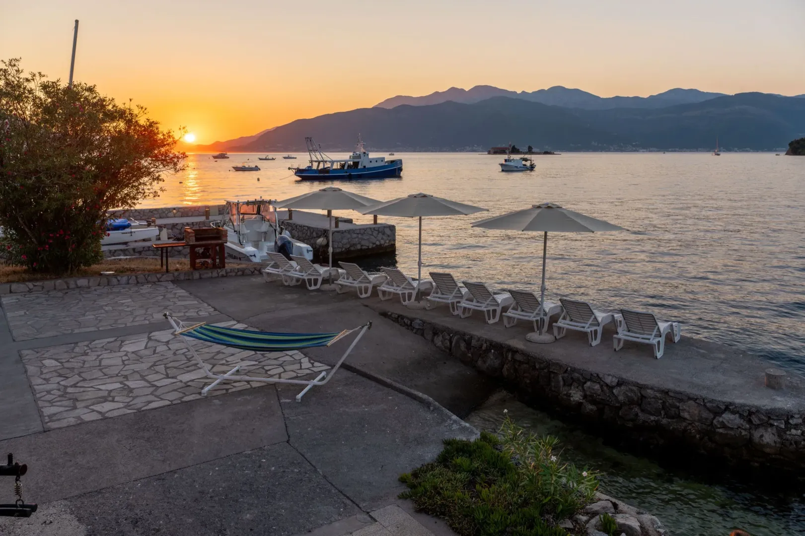 Pogled na more sa popločane terase i privezišta tokom zalaska sunca.