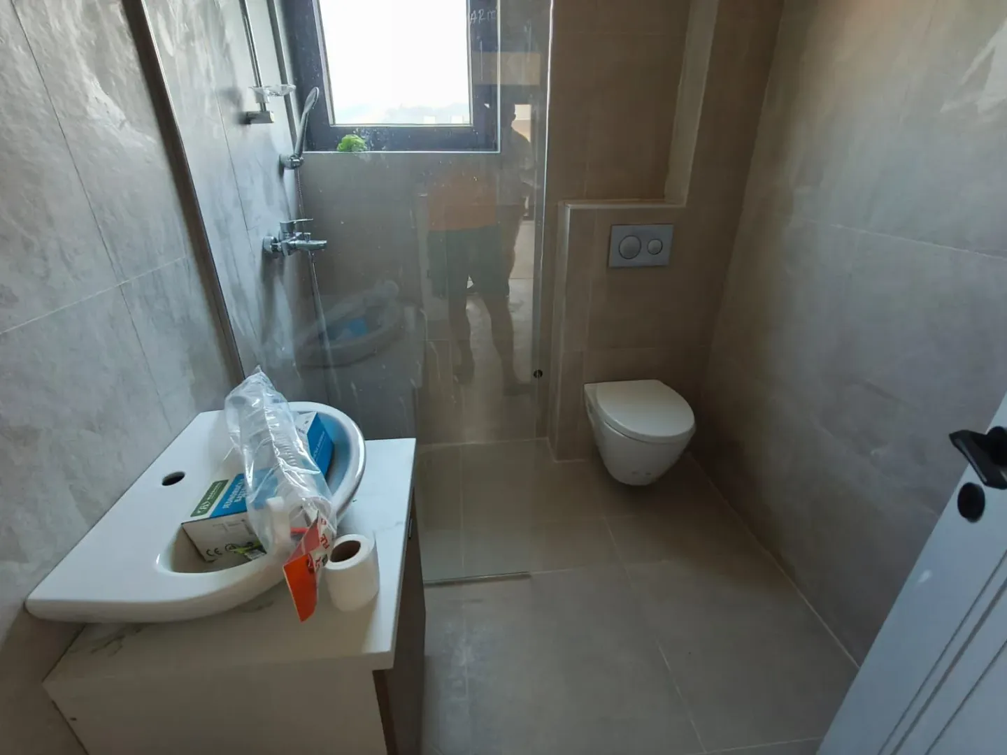 Newly equipped bathroom with a washbasin, toilet, and walk-in shower.