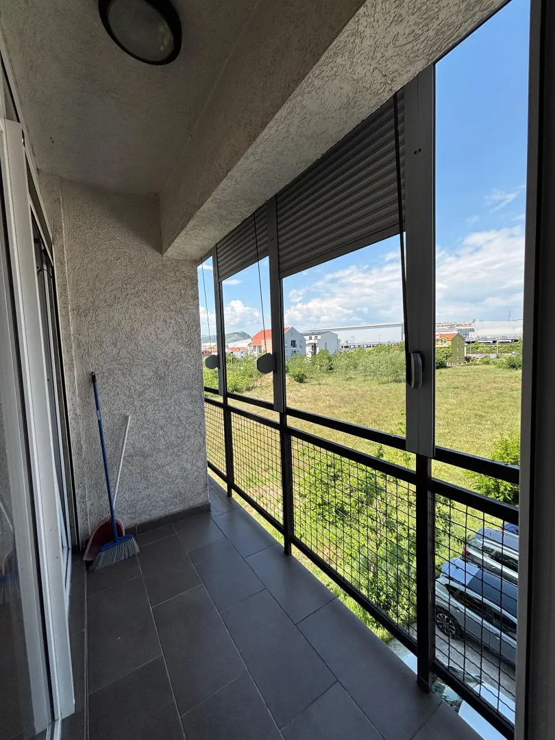 Enclosed balcony with a view of the surroundings and parked cars.