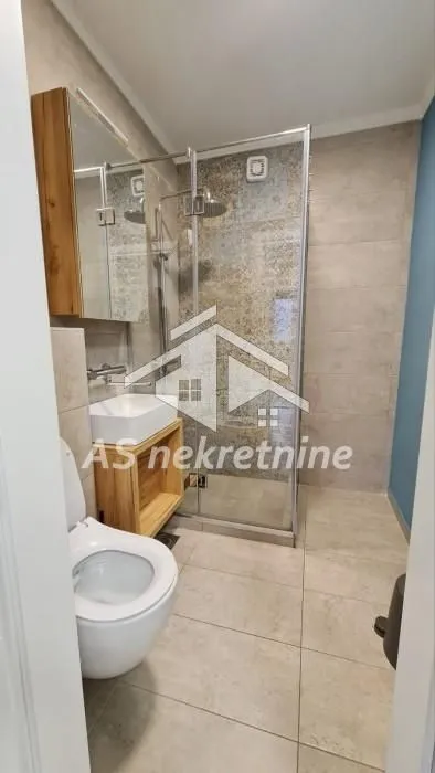 Moderno opremljeno kupatilo sa tuš kabinom i umivaonikom.