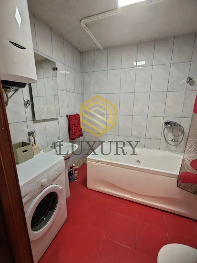 Compact bathroom with a bathtub, washbasin and washing machine.