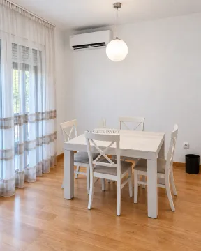 Dining area with a white table and four chairs next to the balcony door. - image 3