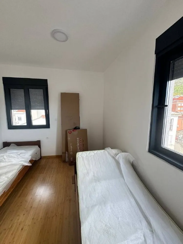 Manja spavaća soba sa dva kreveta i bijelim zidovima.