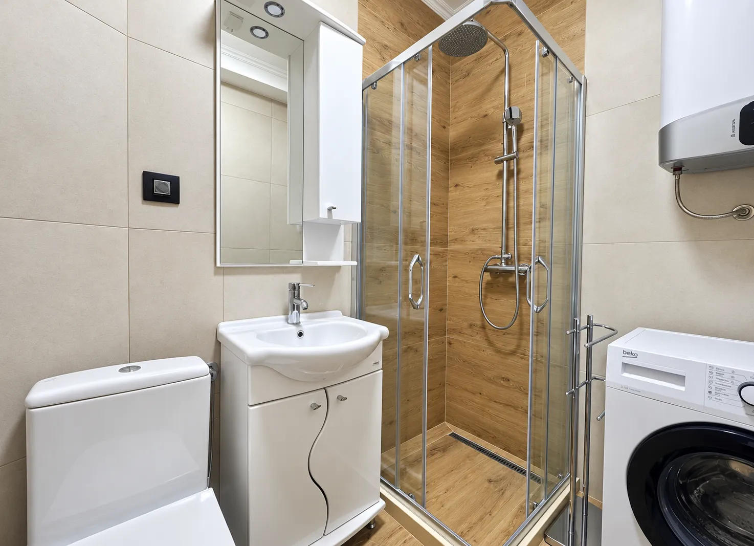 Modernly equipped bathroom with a shower cabin, sink, and washing machine.