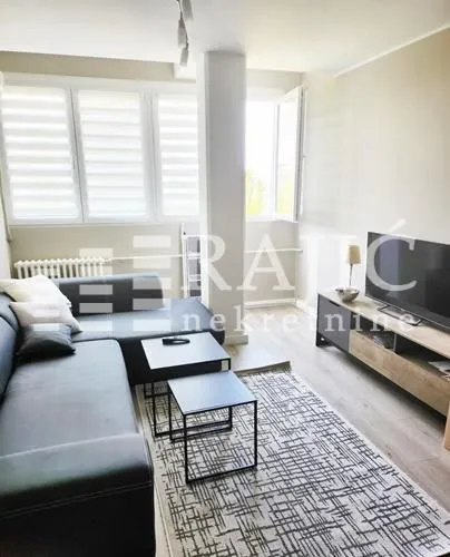 Living room with sofa, television, and coffee tables.
