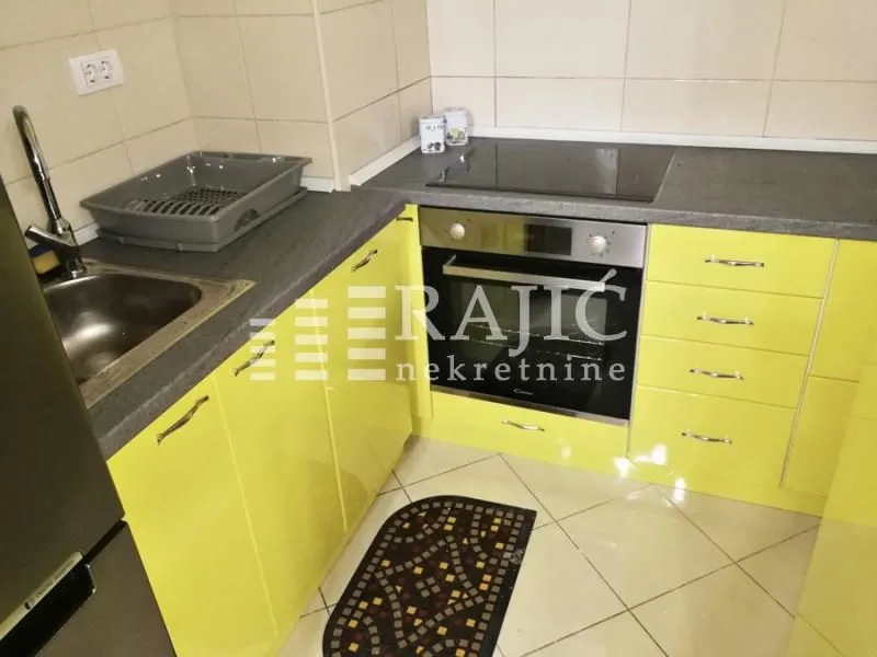 Small kitchen with yellow cabinets and a built-in oven.