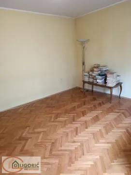 Living room with parquet flooring and a small table with a pile of books. - image 3