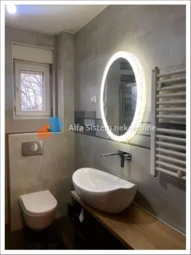Modern bathroom with a washbasin, wall-hung toilet, and illuminated mirror. - image 9