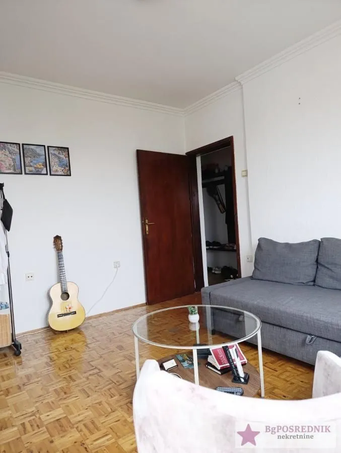 Dnevna soba sa garniturom, stočićem i gitarom.