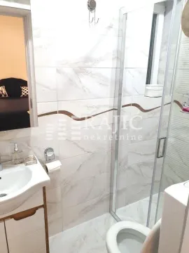 Small bathroom with a shower cabin, sink, and toilet. - image 16