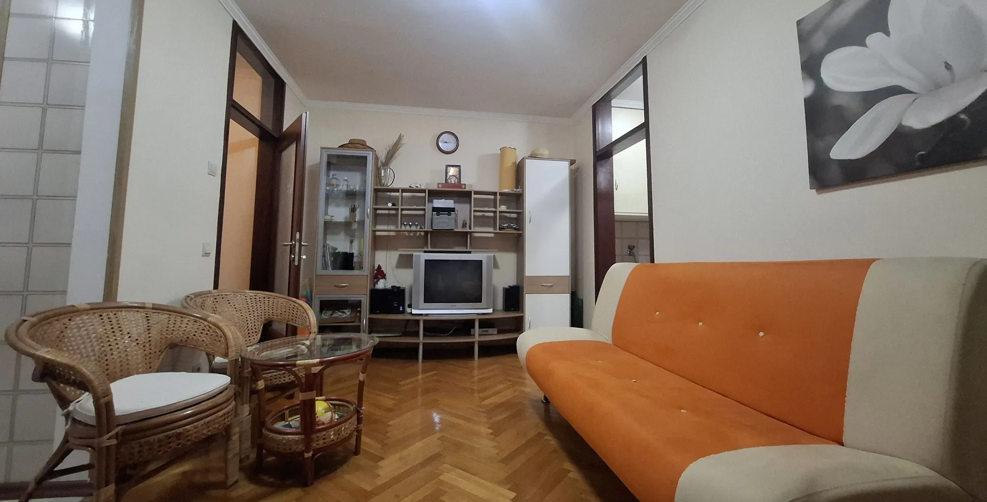 Dnevna soba sa garniturom, foteljama i televizorom.