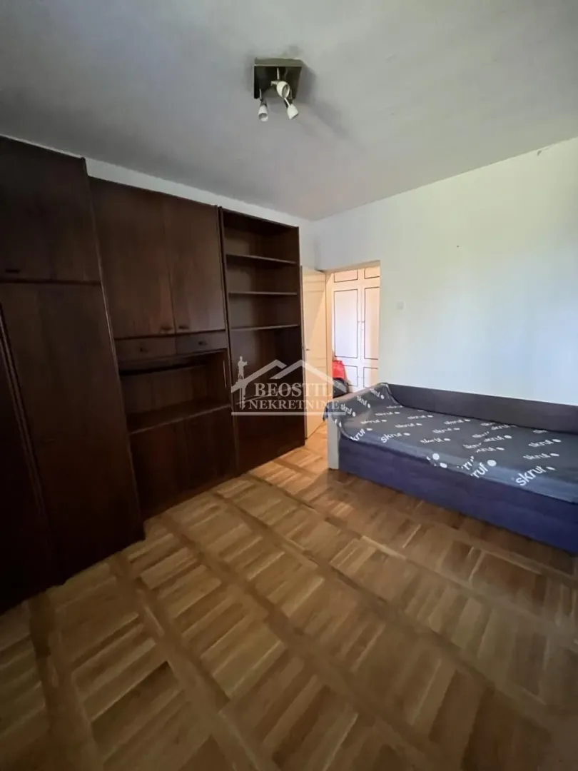 Smaller bedroom with a bed and wooden wardrobes.