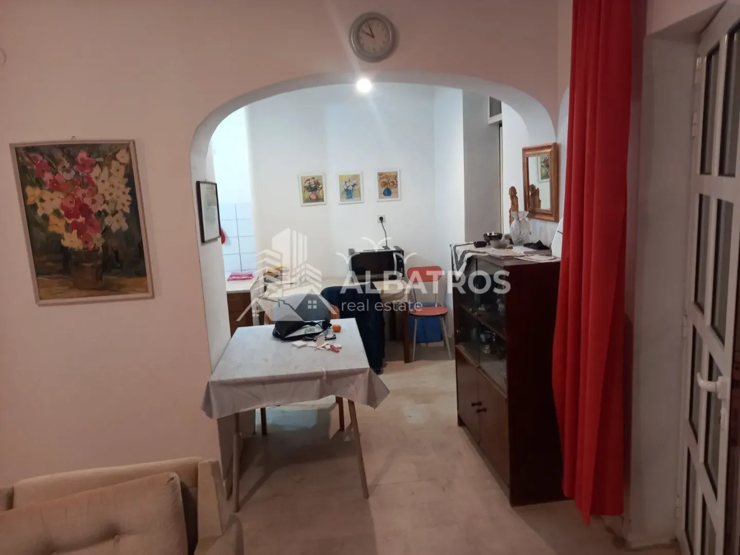 Living room with a dining table and an arched doorway leading to the kitchen.