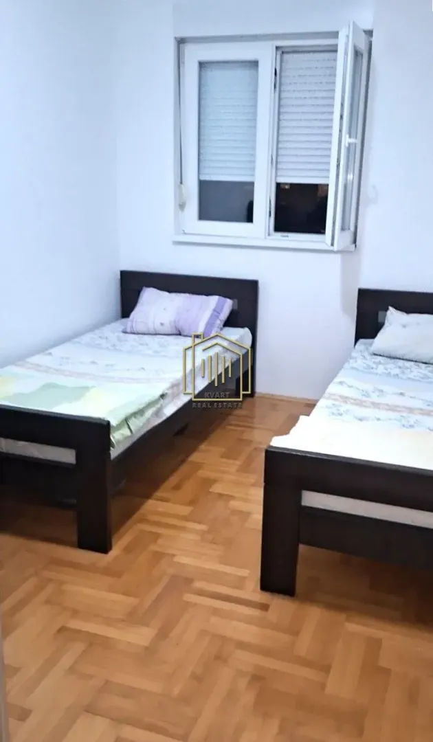 Spavaća soba sa dva kreveta i prozorom.