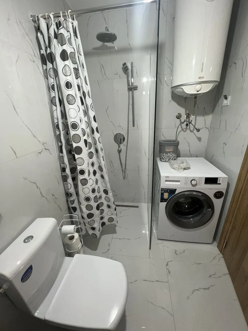 Bright bathroom with a shower, washing machine, and boiler.