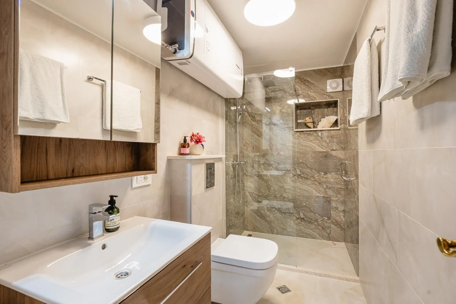 Moderne kupatilo sa umivaonikom, WC šoljom i tuš kabinom.