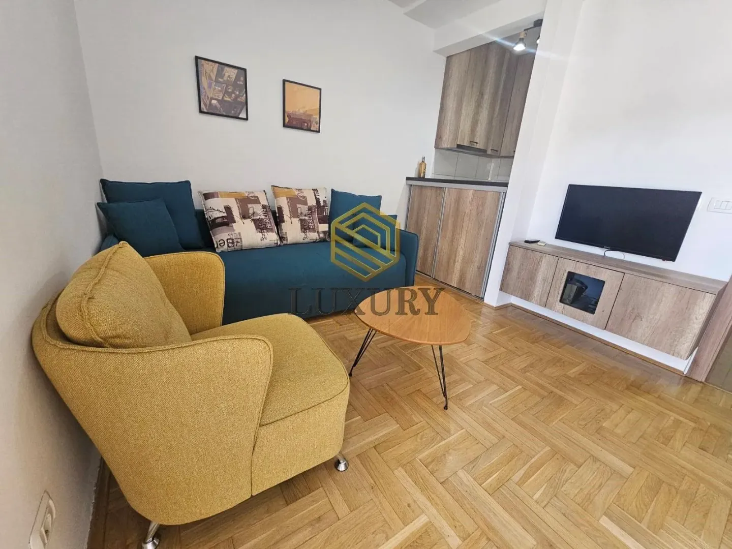Living room with a sofa, armchair and a kitchen area.