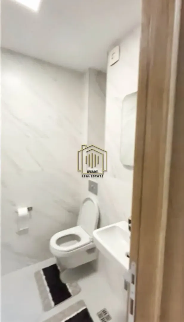 Manje kupatilo sa bijelim pločicama i ugradnom sanitarijom.