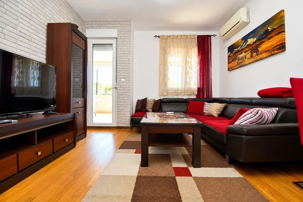 Furnished living room with a sectional sofa, TV, and access to the terrace.