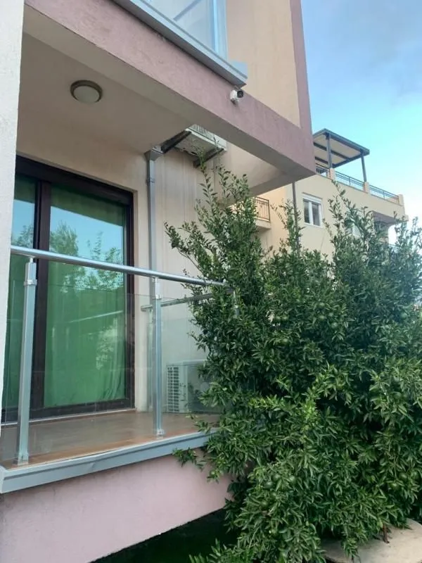 Small balcony with a glass railing and a view of greenery.