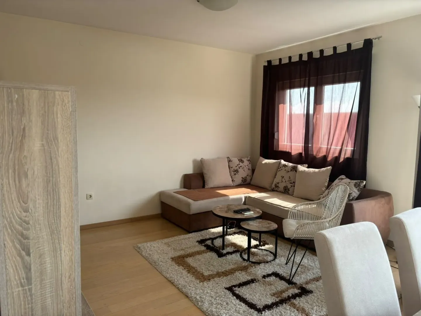 Living room with a sectional sofa, small tables, and a window with dark curtains.