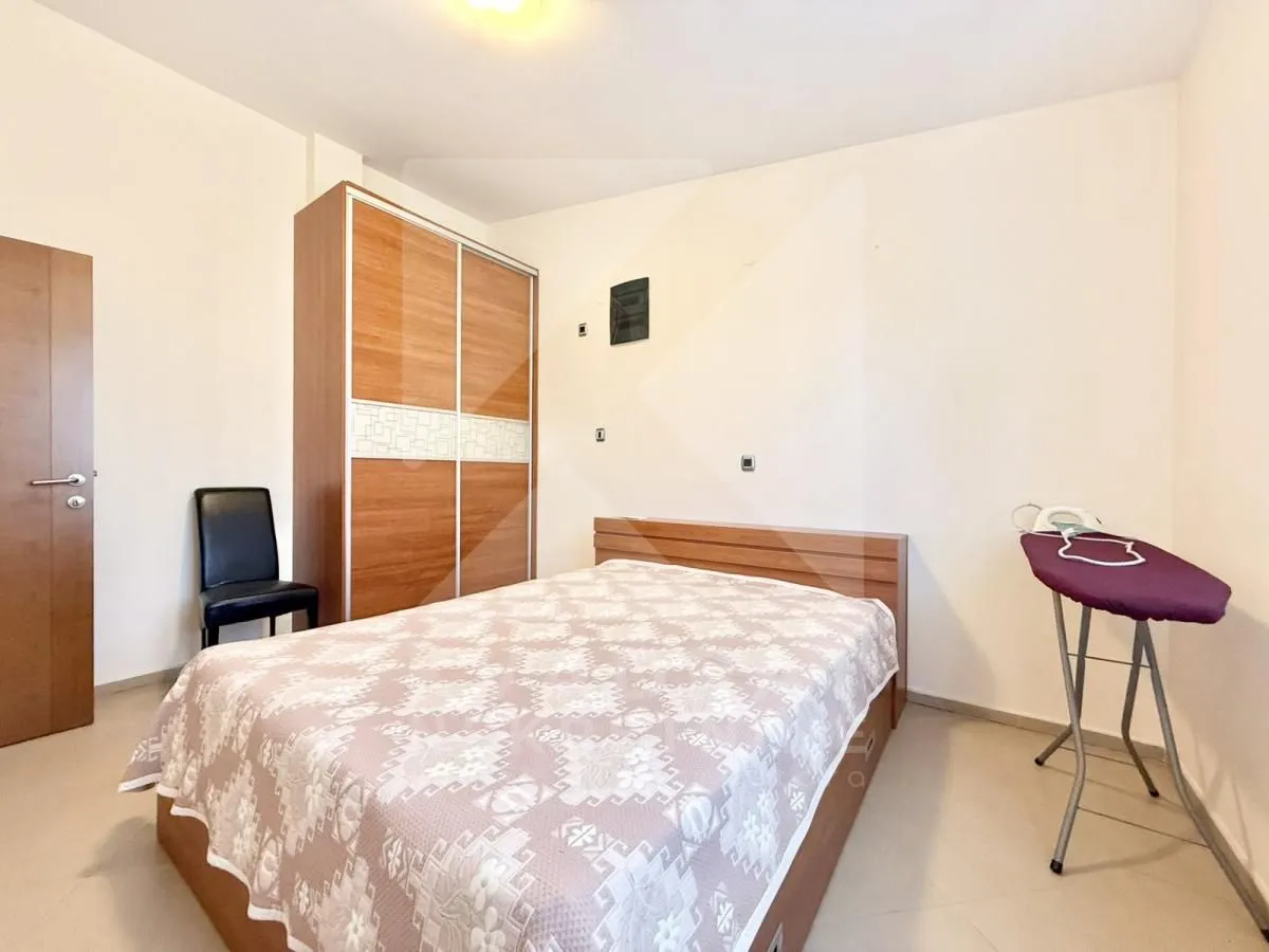 Furnished bedroom with a double bed, wardrobe, and ironing board.
