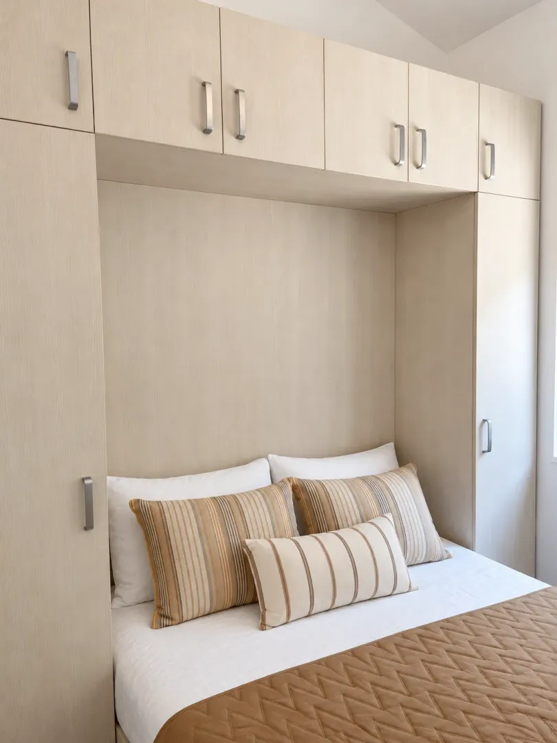 Furnished bedroom with built-in closets above the bed.