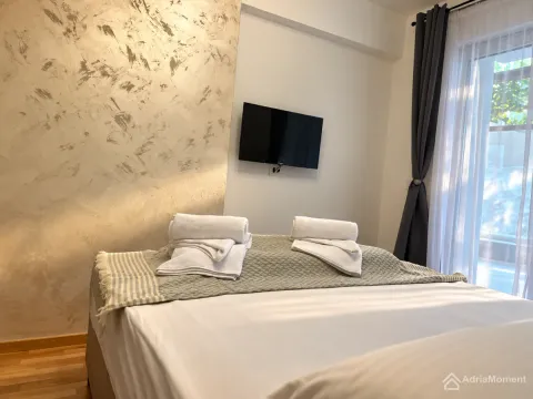 Spavaća soba sa bračnim krevetom i televizorom na zidu. - image 3