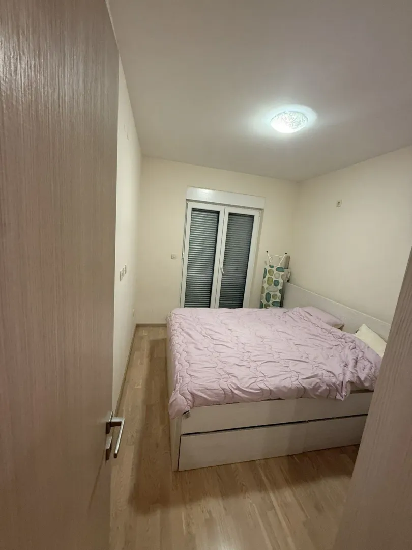 Jednostavna spavaća soba sa bračnim krevetom i svijetlim podovima.