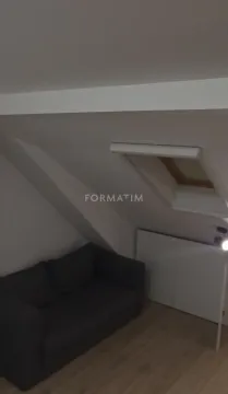 Manji dnevni boravak u potkrovlju sa tamnim kaučem i krovnim prozorom. - image 7