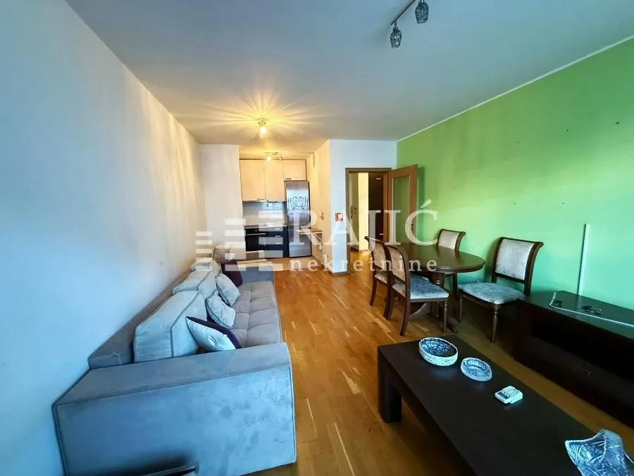 Living room with a sofa, dining area, and a view of the kitchen.