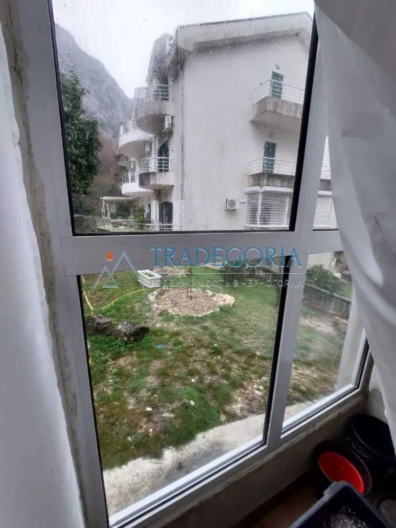 Pogled kroz prozor na okolne zgrade i dvorište.