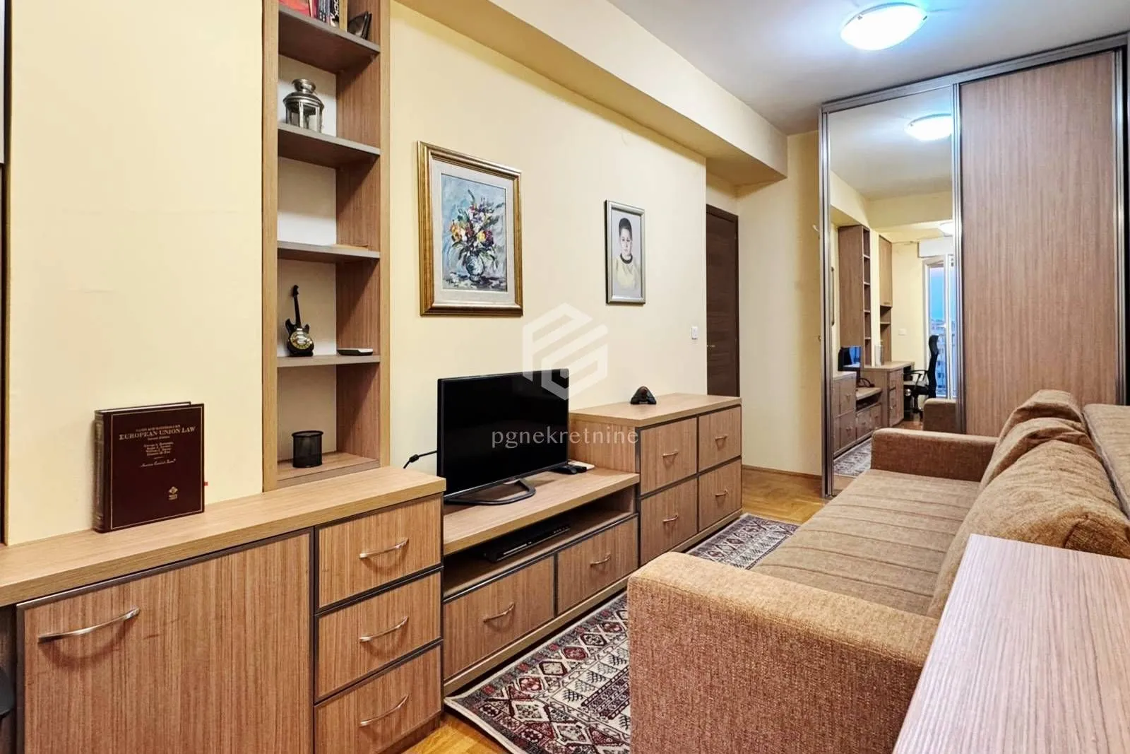 Living room with a sofa, TV unit and a built-in mirrored wardrobe.