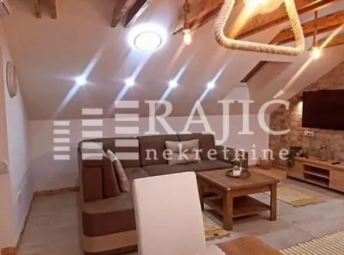 Living room with a sofa and wooden ceiling beams.