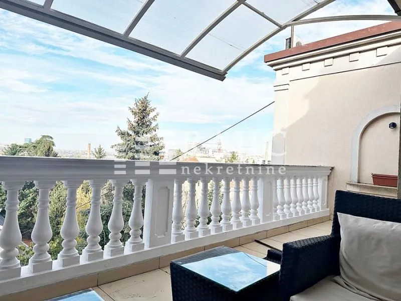 Spacious balcony with seating furniture and a view.