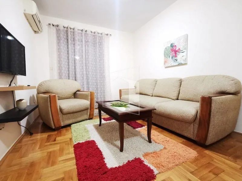 Living room with a seating set, coffee table, and a wall-mounted TV.