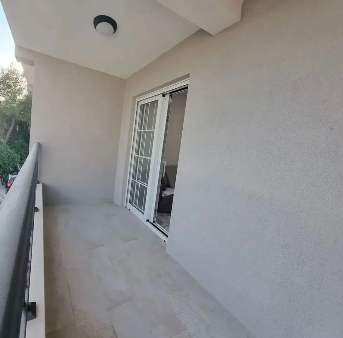 Spacious covered balcony with tiled flooring and sliding glass doors.
