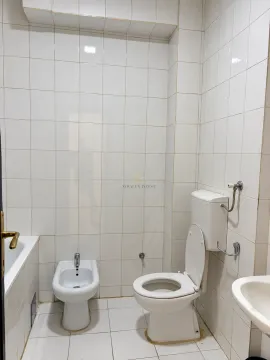 Bathroom equipped with a toilet, bidet, bathtub, and sink, tiled with white tiles. - image 11