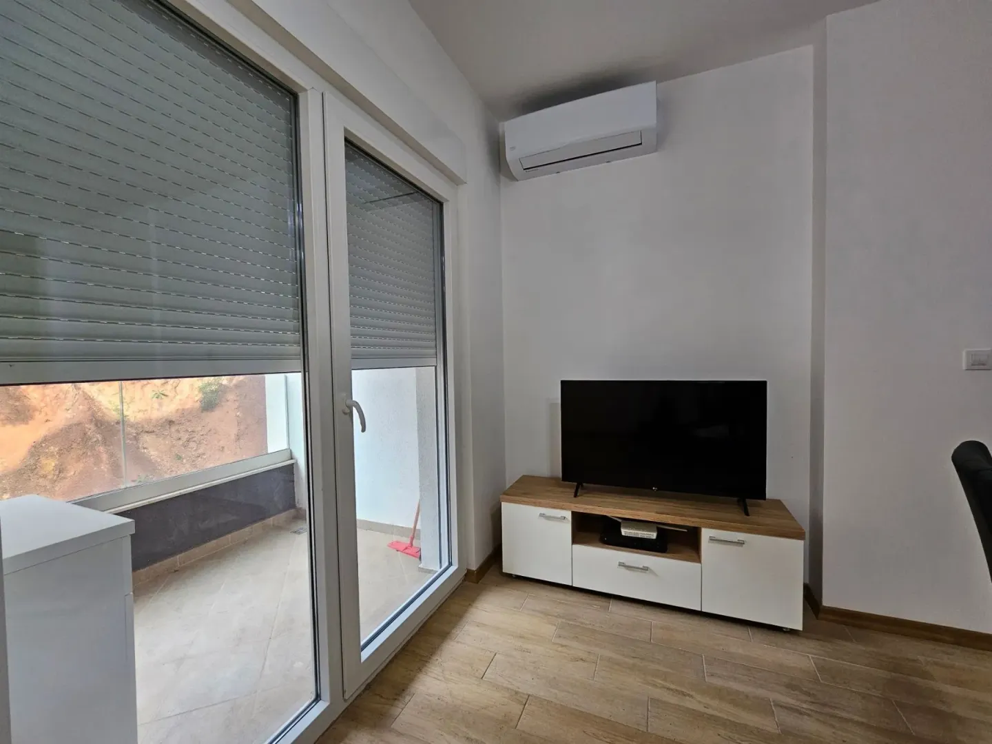 Living room with a TV, air conditioning unit, and access to the terrace.