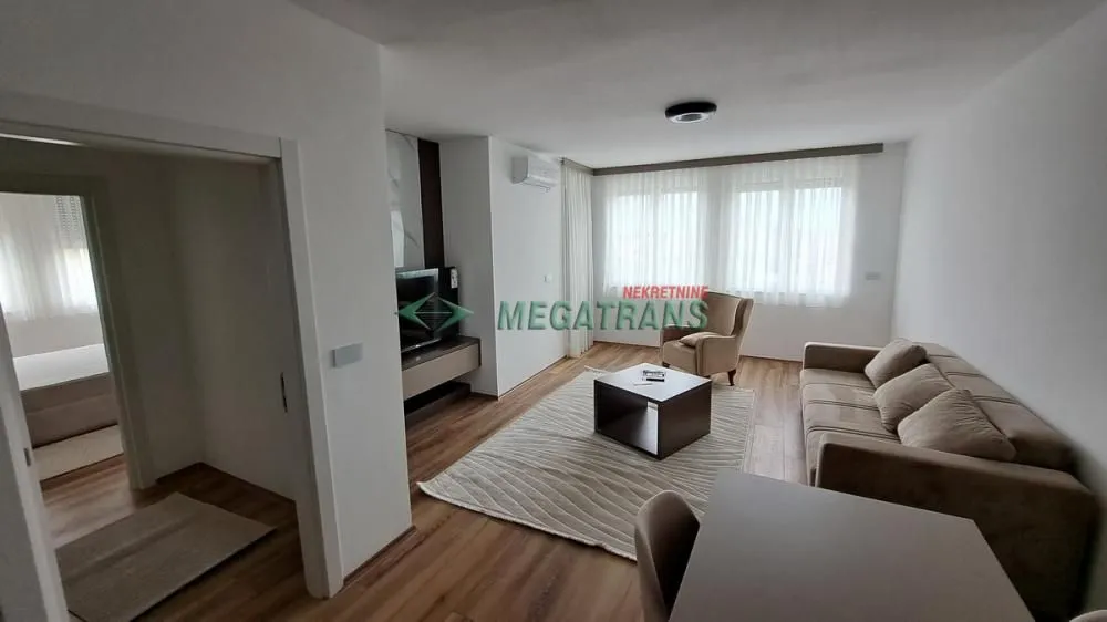 Nameštena dnevna soba sa garniturom i televizorom.