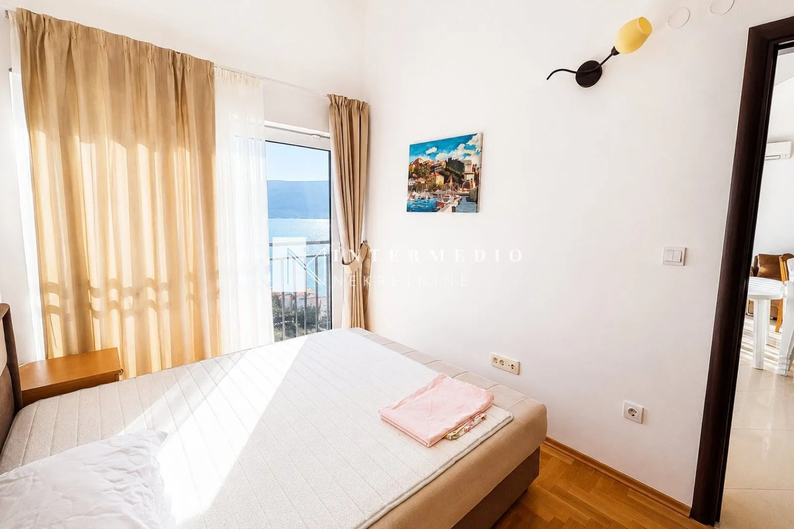 Spavaća soba sa bračnim krevetom i izlazom na balkon sa pogledom na more.