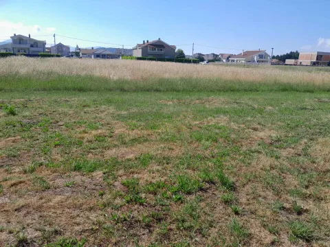 Pogled na ravan plac sa travnatom površinom i okolnim kućama u pozadini. - image 3
